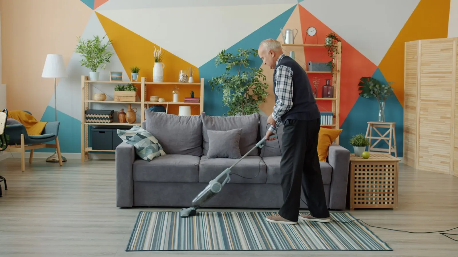 An older man vacuuming a living room rug